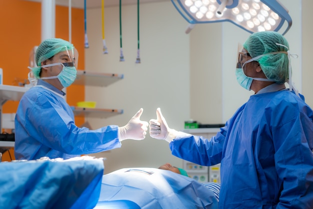 Het team van chirurgen in volwassen uniform en masker toont een dreun in de operatiekamer