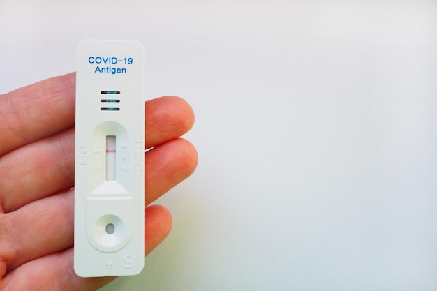 Het testresultaat voor COVID-19 is negatief, niet geïnfecteerd, met behulp van sneltestapparatuur. Test voor coronavirus op de hand, witte achtergrond. Ruimte kopiëren. Testconcept Coronavirus Ziekte-infectie.