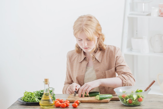 Het tienermeisje bereidt thuis salade voor