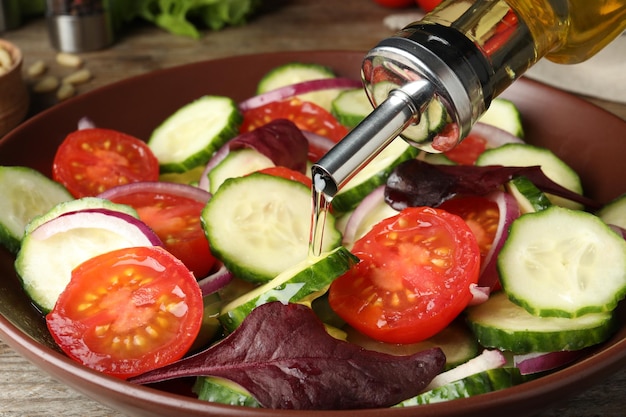 Foto het toevoegen van kookolie aan een heerlijke salade op tafel close-up