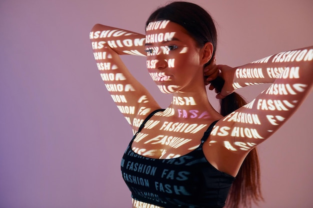 Het tonen van lichaam en zwart ondergoed Mooie jonge vrouw is in de neonlichten van de projector in de studio