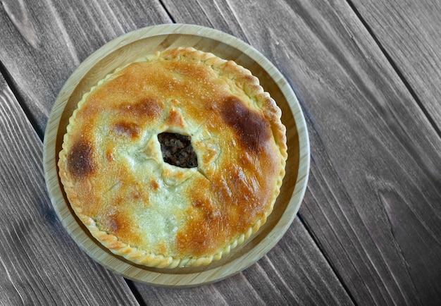 Het traditionele gerecht van de volkeren van de Kaukasus is Karachai khychins Ossetische taarten met vlees op een houten bord Lichte houten achtergrond bovenaanzicht kopieerruimte