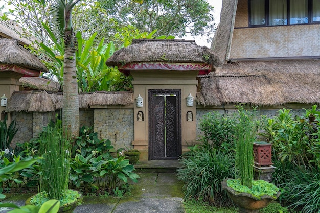 Het trottoir leidt naar een huis met Balinese sculpturen op een tropisch tuineiland Bali, Indonesië