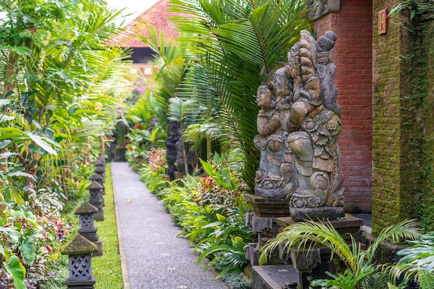 Het trottoir leidt naar een huis met balinese sculpturen op een tropisch tuineiland bali, indonesië