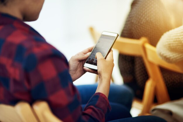 Foto het uitwerken op zijn mobiele telefoon shot van een jonge man die een mobiele telefoon gebruikt in een kantoor