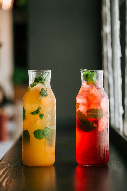 Het vers fruitlimonade van glaskruiken op houten lijst