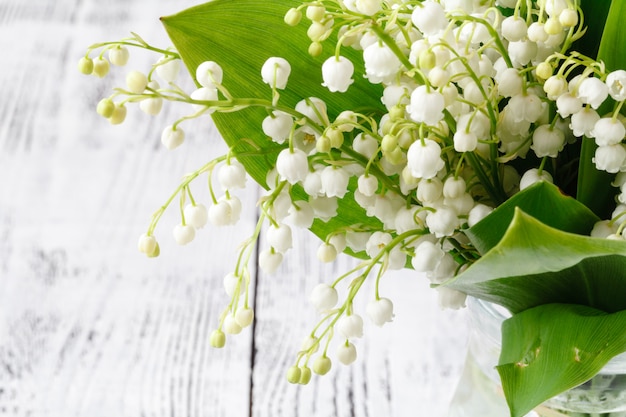 Het verse boeket van de lentebloemen met lelietje-van-dalen op een houten lijst