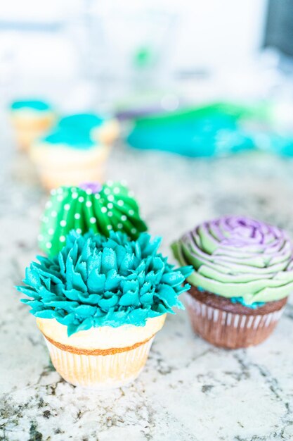 Foto het versieren van cupcakes met cactusvormige botercrème glazuur