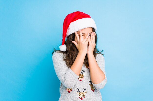 Het vieren van het meisje Kerstmisdag knipoogt door angstig en zenuwachtige vingers.