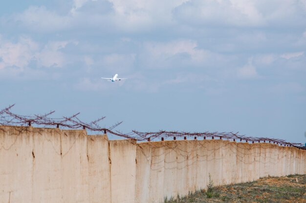 Het vliegtuig in de lucht tegen de achtergrond van een betonnen muur met prikkeldraad evacuatie ontsnapping