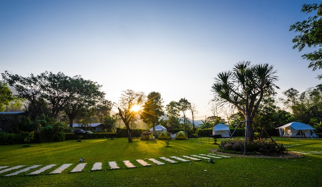 Het voetpad op groene gazons en tent met zonsopgang in de tuin