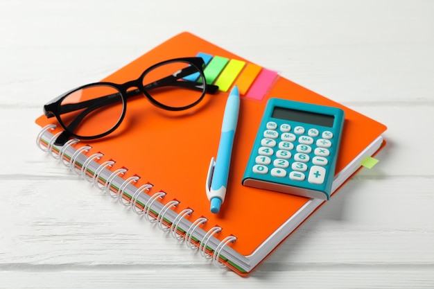 Het voorbeeldenboek, de glazen, de calculator, de pen en de stickers op houten, sluiten omhoog