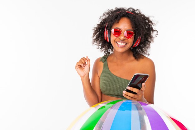 Het vrij Afrikaanse wijfje in zwempak bevindt zich met grote kleurrijke rubberbal, luistert aan muziek met oortelefoons en doet selfie geïsoleerd