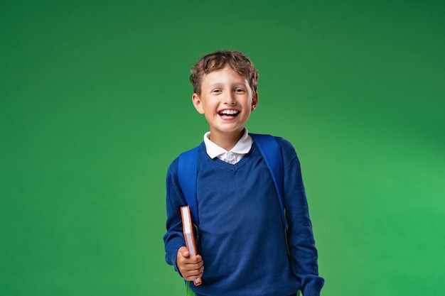 Foto het vrolijke boek en de rugzak van de schooljongenholding