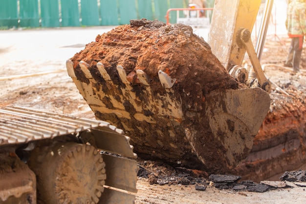 Het vuile graafwerktuig van de backhoebouwwerf met het graven van landgrond bij plicht het werken graaft voor pijp