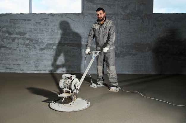 Het vullen van de vloer met beton, dekvloeren en het egaliseren van de vloer door bouwvakkers. Gladde vloeren gemaakt van een mengsel van cement, industrieel beton