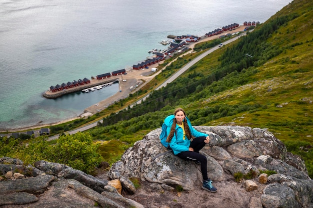 Het wandelaarmeisje zit op rotsen op Offersykammen-sleephoofd en bewondert panorama van lofoten-eilanden, Noorwegen