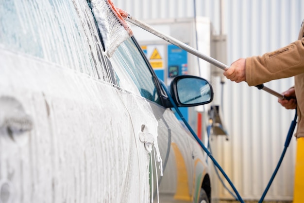 het wassen van een auto met een borstel en zeepschuim alvorens het te reinigen met een jet wash in de open lucht