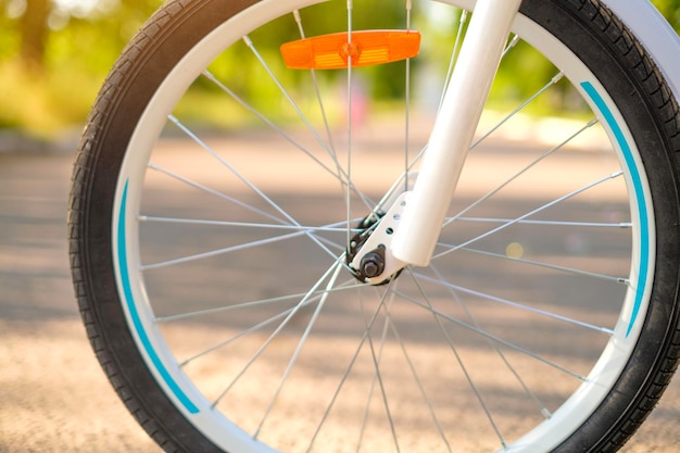 Het wiel van kinderfiets in de stralen van de ondergaande zon