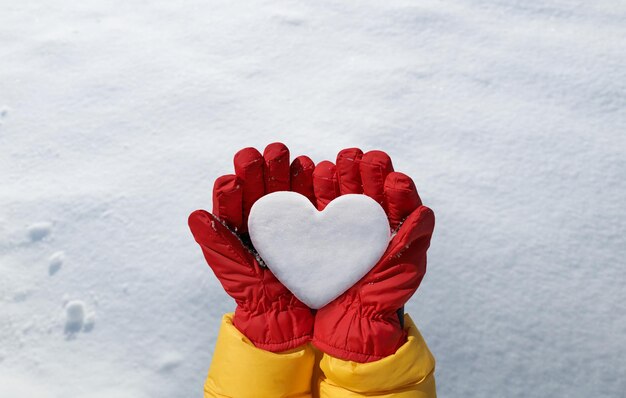 Het wijfje dient rode handschoen in houdt sneeuwhart op sneeuwachtergrond