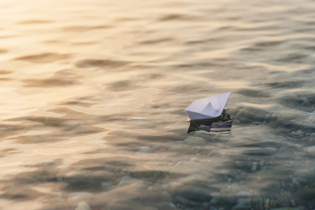 Het Witboekboot van de origami op blauw diep water.