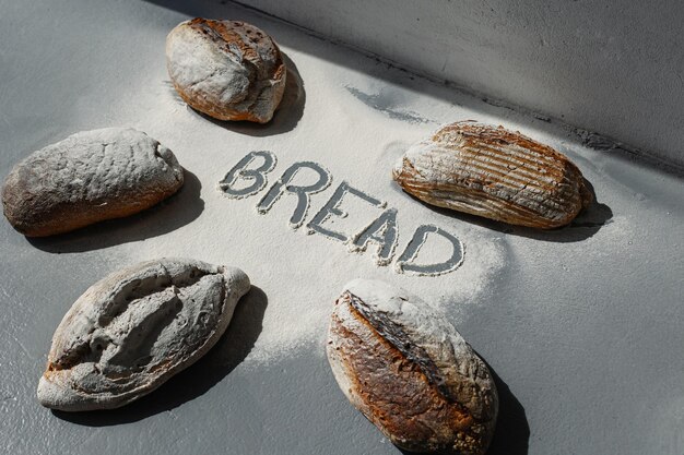 Het woord brood in bloem tussen verschillende broden op een grijze achtergrond