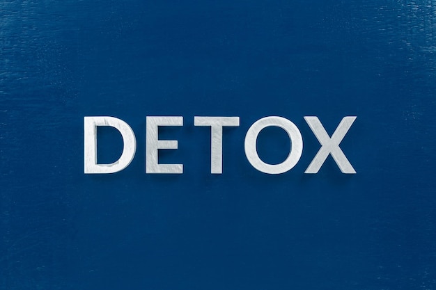 Het woord detox gelegd met zilveren letters op een klassiek blauw, plat geverfd oppervlak Gezond eten of dieetconcept