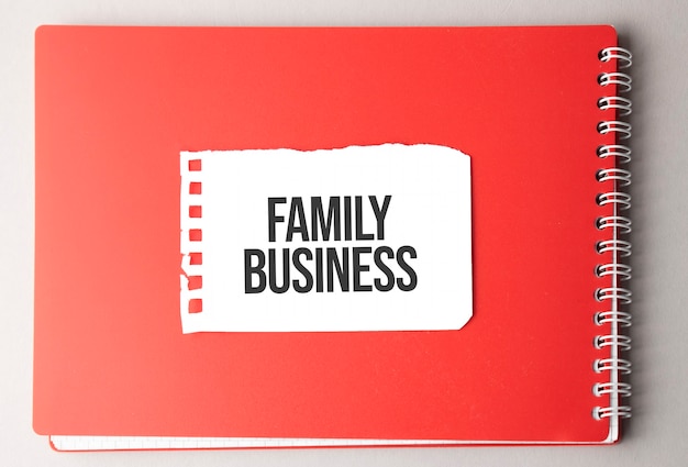Het woord FAMILIEBEDRIJF op gescheurd papier op rode blocnote.
