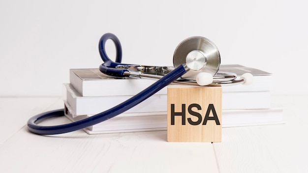 Het woord HSA is geschreven op een houten kubus in de buurt van een stethoscoop op een wit medisch concept als achtergrond