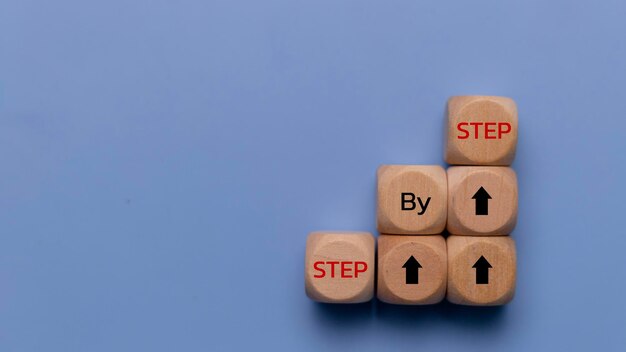 Het woord stap voor stap op houten blokjes Prestaties of vooruitgang in de zakelijke carrière