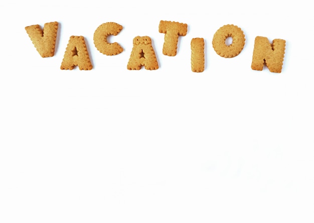 Het woord VAKANTIE gespeld met alfabet vormige koekjes, op witte achtergrond met vrije ruimte voor ontwerp en tekst