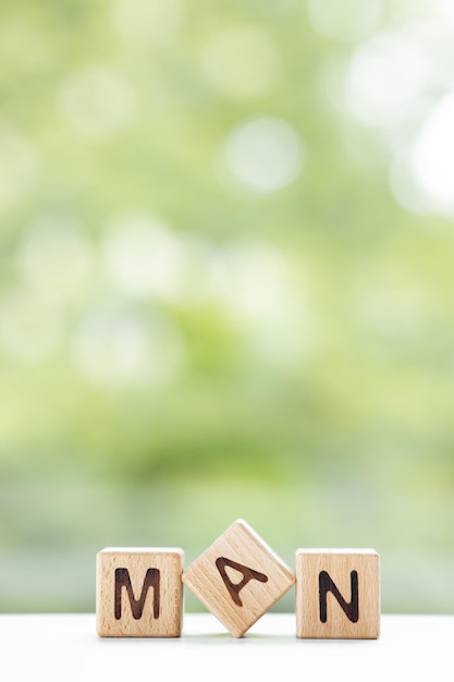 Het woord van de mens is geschreven op houten kubussen op een groene zomerachtergrond Close-up van houten elementen