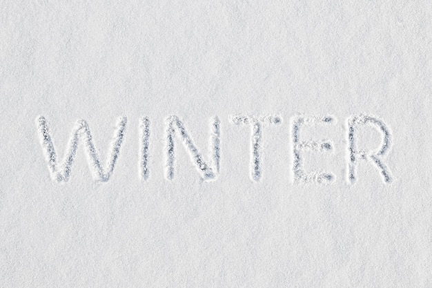 Het woord winter geschreven in verse sneeuw op de drempel van het einde van de herfst en voor het begin van het nieuwe jaar en de kerstvakantie.
