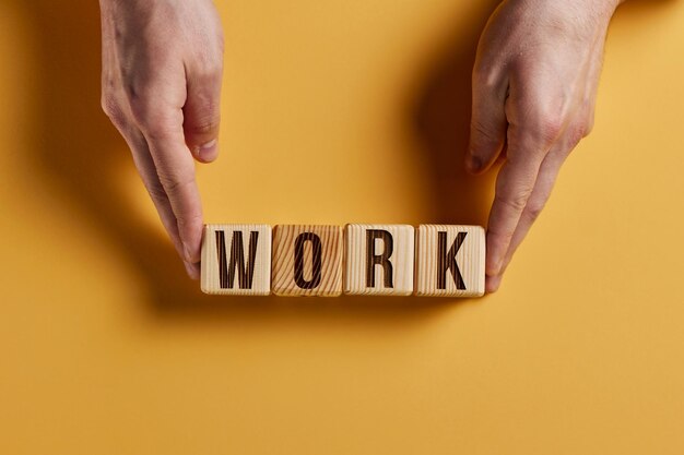 Foto het woord work is geschreven in houten blokjes in zwarte letters op een gele achtergrond