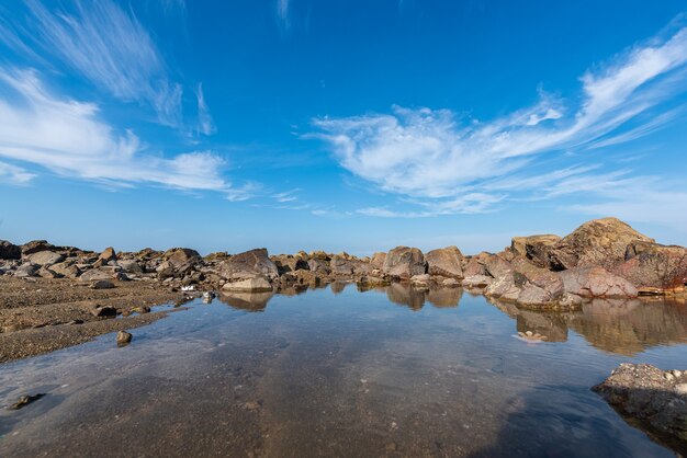 Het zeewater tussen de kustriffen weerspiegelt de gele riffen en de blauwe lucht