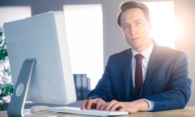 Het zekere zakenman typen op computer en het bekijken camera