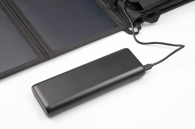 Het zonnepaneel laadt de powerbank-batterij voor de smartphone op een wit op. digitale technologieën en apparaten