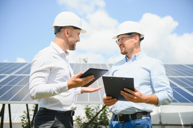 Het zonnepark (zonnepaneel) met twee ingenieurs lopen om de werking van het systeem te controleren, alternatieve energie om 's werelds energie te besparen, fotovoltaïsche module-idee voor de productie van schone energie