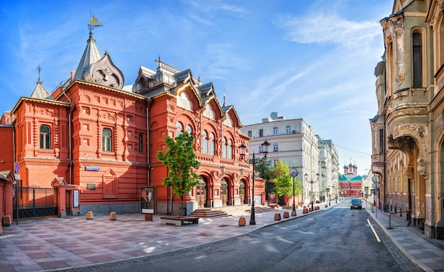Het zonnige rode bakstenen Theater van Naties in Petrovsky Lane in Moskou en de tempel van het Petrovsky-klooster in de verte