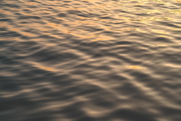 Het zonsondergangwater wijst op rimpelingen bij zonlicht Abstracte gouden bezinning op waterzonsondergang