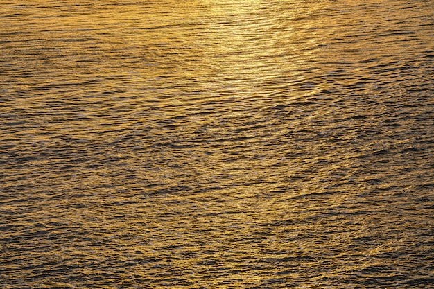 Het zonsondergangwater wijst op rimpelingen bij zonlicht Abstracte gouden bezinning op waterzonsondergang