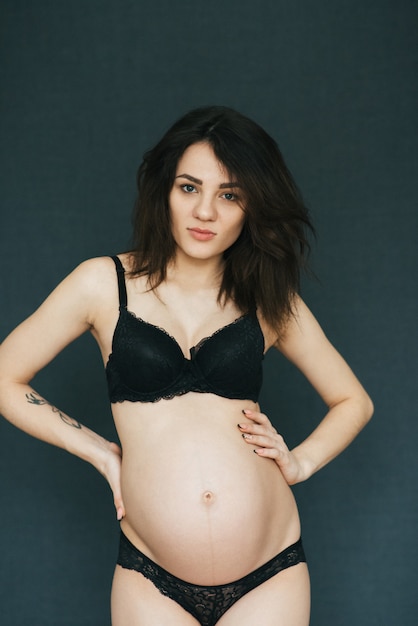 Het zwangere donkerbruine meisje stellen in lingerie