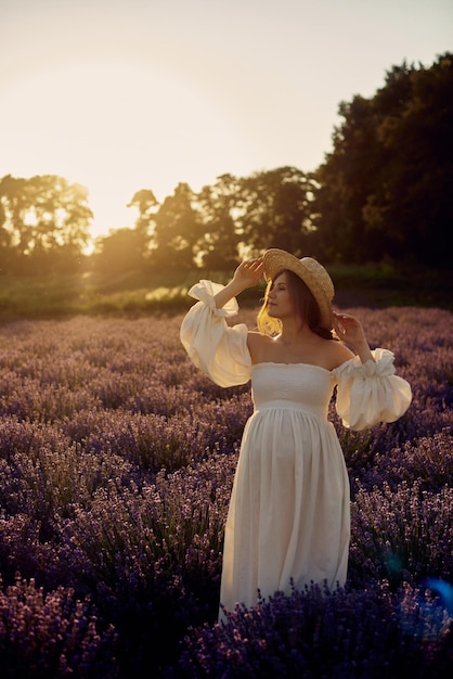 Het zwangere meisje met een hoed in het lavendelveld op een zonsondergang