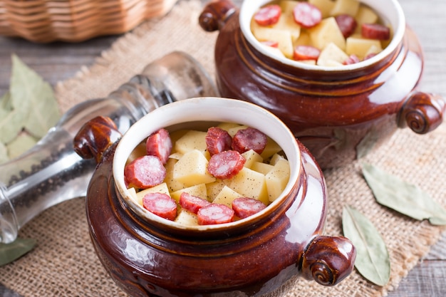 Hete aardappelgoulash met spek en worstjes geserveerd in een keramische kom