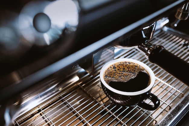 Hete americano op de koffiemachine in het café met soft-focus en over licht op de achtergrond