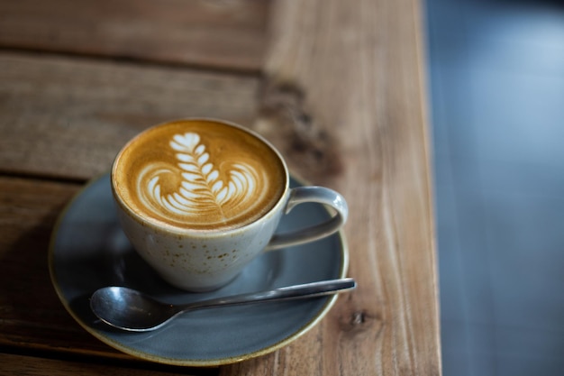 Hete cappuccino-koffiekopje met hartvorm latte art op bruine oude houten tafel in café