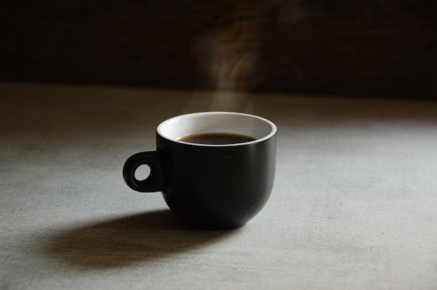 Foto hete espresso in een zwarte kop op een grijze achtergrond