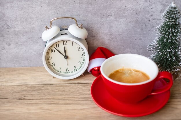 Hete espressokoffie en vintage klok op tafel, rode koffiekop in café of thuis in de ochtend. activiteit, dagelijkse routine, ochtend, training en werk-privébalansconcept