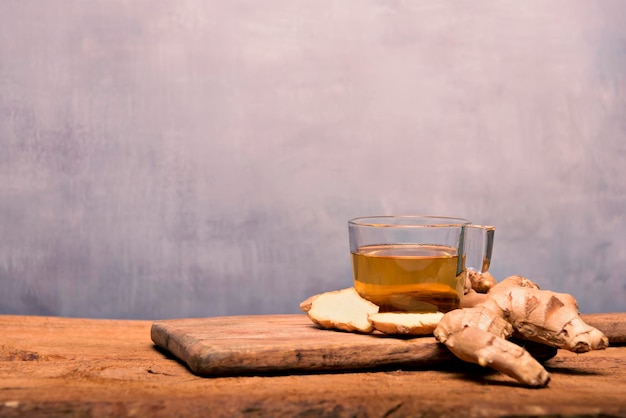 Hete gingerinfused cup op een witte tafel met gesneden gemberwortel in een kom bovenaanzicht