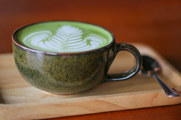 Hete groene theematcha latte in kop op lijst.